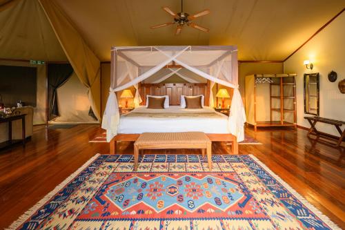 a bedroom with a bed in a tent with a rug at Olare Mara Kempinski in Talek