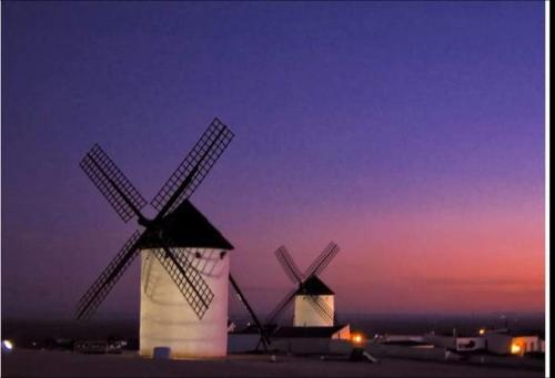 two large windmills are lit up at night at Hostal Restaurante Ego's in Campo de Criptana