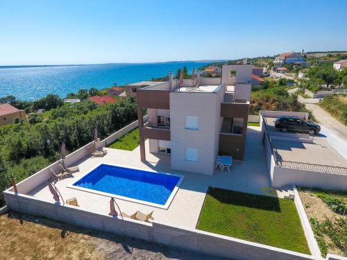 a house with a swimming pool next to the ocean at Zrno soli in Rtina