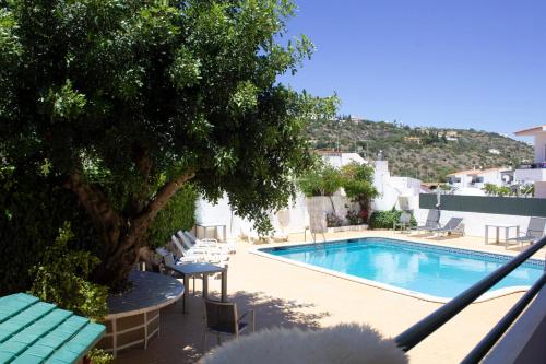 uma piscina com cadeiras e uma árvore ao lado em AAA Ana Albufeira Apartments em Albufeira