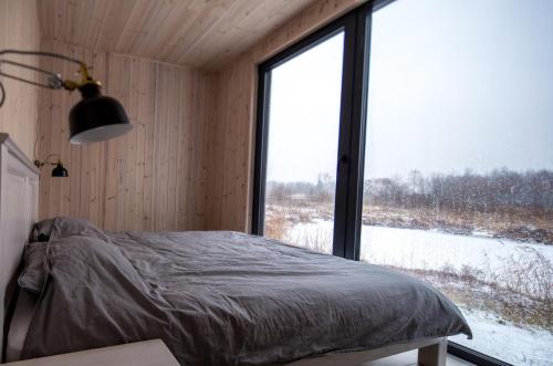 ein Schlafzimmer mit einem Bett und einem großen Fenster in der Unterkunft TAURO TROBA “The Ox Shelter” in Stragutė