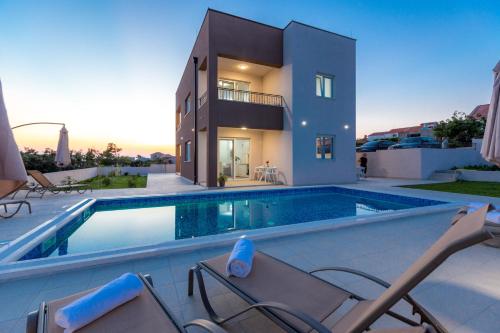 a villa with a swimming pool in front of a house at Zrno soli in Rtina