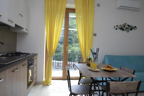 a kitchen with a table and yellow curtains and a window at Casa Nanà Amalfi Coast in Vietri sul Mare