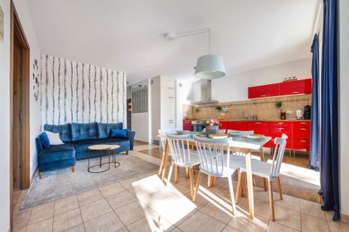 a kitchen and living room with a blue couch and a table at Apartamenty Sun & Snow Kasprowicza in Kołobrzeg