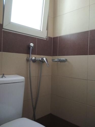 a shower in a bathroom with a toilet and a window at Pella Inn Hostel in Athens