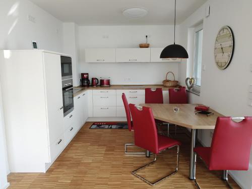 a kitchen with a wooden table and red chairs at Ferienwohnung Seenland in Großräschen