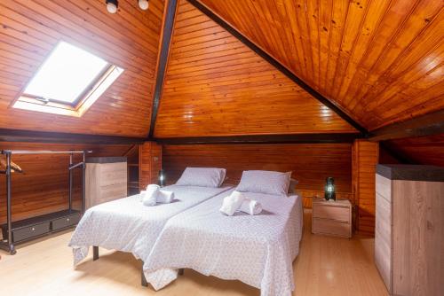 une chambre avec deux lits dans une pièce avec des plafonds en bois dans l'établissement Villa Sol e Mar, à Charneca