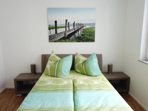 a bed with pillows and a picture of a pier at Ferienwohnung Seenland in Großräschen