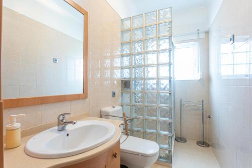 une salle de bain avec un lavabo, des toilettes et un miroir dans l'établissement Villa Sol e Mar, à Charneca