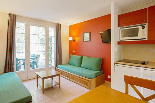 a living room with a couch and a microwave at Residence du Lac - maeva Home in Monflanquin