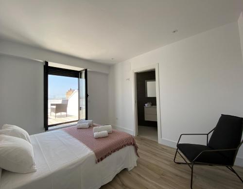 a bedroom with a bed and a chair and a window at Aticos Concepción Centro in Córdoba