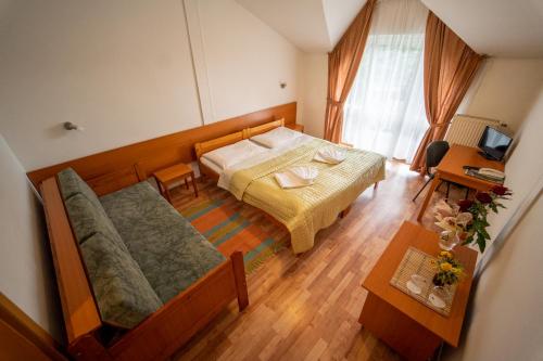 um pequeno quarto com uma cama e um sofá em Park Hotel Čingov em Smizany