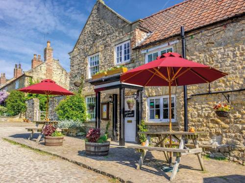two tables with umbrellas in front of a building at The Fauconberg in Coxwold
