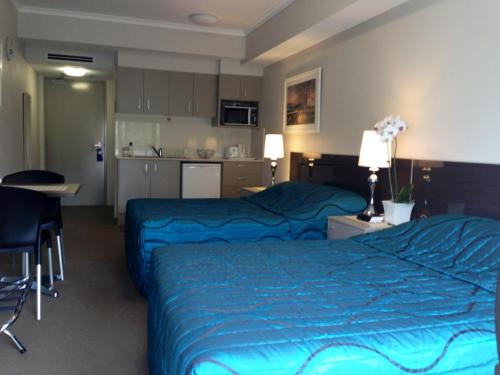a hotel room with two beds and a kitchen at Strathfield Executive Accommodation in Sydney