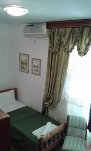 a bedroom with a green bed and a window at Pansion Mimoza in Herceg-Novi