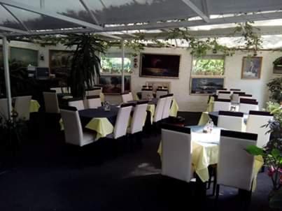 a dining room with tables and white chairs at Pansion Mimoza in Herceg-Novi