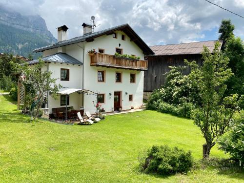 a large white house with a large yard at Dolomites Charme Chalet in Colle Santa Lucia