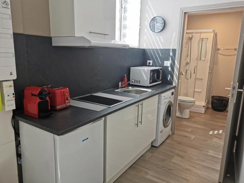 a kitchen with white cabinets and a red appliance at Suite Orphelins 2 (rdc) in Reims