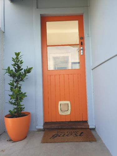 an orange door with a potted plant in front of it at Pura Vida by the Sea in Riverton