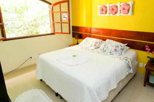 a bedroom with a large white bed with a window at Pousada Rio Bracuhy in Angra dos Reis