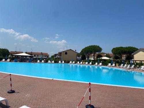 einen großen blauen Pool mit weißen Stühlen und Tischen in der Unterkunft Villaggio Teodorico in Punta Marina