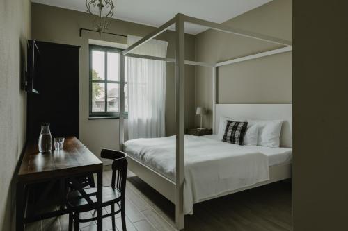 a bedroom with a canopy bed with a table and a desk at Villa Antiqua in Racibórz