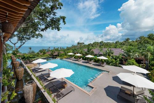 une image d'une piscine dans un complexe avec des parasols dans l'établissement Camia Resort & Spa, à Duong Dong