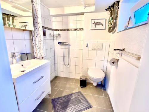 a white bathroom with a sink and a toilet at Modernes Zimmer mit Küchenzeile und Bad in Groß Denkte
