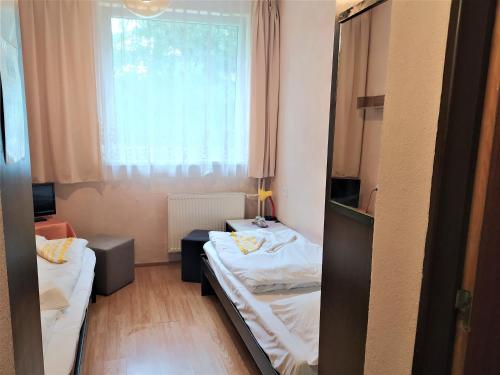 a small room with two beds and a window at Hotel Tatranec in Tatranská Lomnica