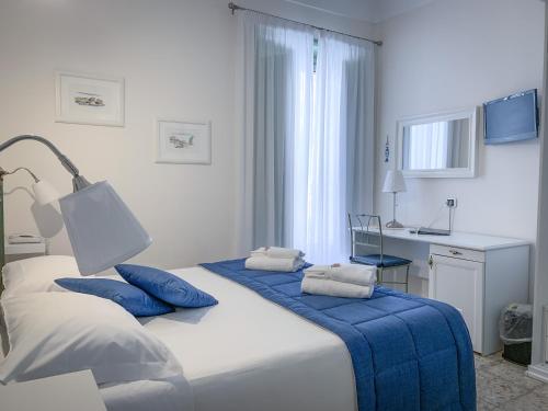 a bedroom with a bed with blue pillows and a desk at Hotel Posta in Siracusa