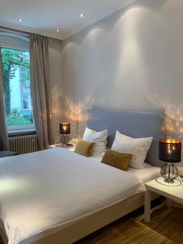 a bedroom with a large white bed with two lamps at Suite Appartement Friesenhof in Hannover