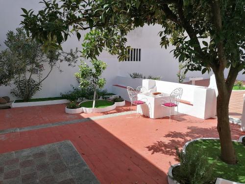 a patio with a table and chairs and a tree at A CASA DA VILA in Almodôvar