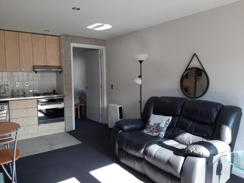 un soggiorno con divano in pelle e una cucina di City Apartment a Christchurch