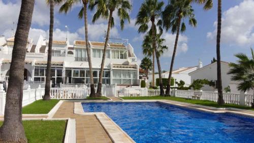 a large white house with a swimming pool and palm trees at Casa Linda in Rojales