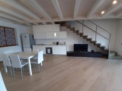 ein Wohnzimmer mit einem Tisch, Stühlen und einer Treppe in der Unterkunft Appartamento DELUXE 1 con vasca idromassaggio vista Lago di Garda, riscaldata, privata e utilizzabile tutto l'anno in Brenzone sul Garda