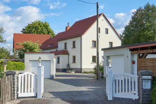 ein weißes Haus mit einem Tor und einer Garage in der Unterkunft Ferienwohnung Erika in Laußnitz