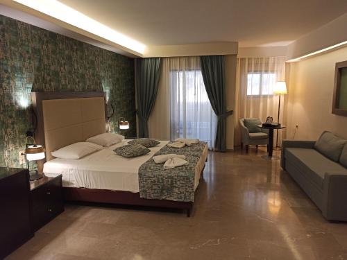 a hotel room with a bed and a couch at King Minos Hotel in Tolo