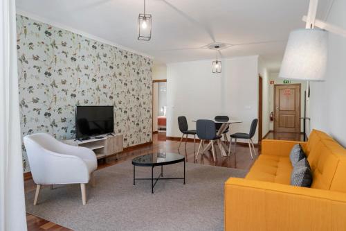 a living room with a yellow couch and a table at Reis Magos IV by An Island Apart in Caniço