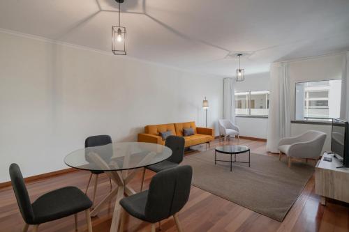 a living room with a glass table and chairs at Reis Magos IV by An Island Apart in Caniço
