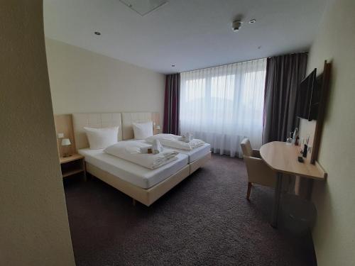 a hotel room with a large bed and a desk at Hotel Siebenschläfer am Wasserturm in Alsdorf