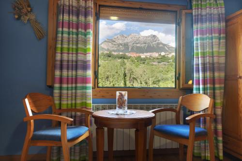 a table and two chairs and a window with a mountain at Hotel Cinca in Escalona