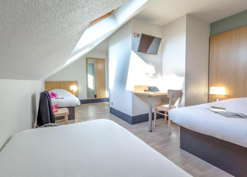 a hotel room with two beds and a desk at B&B HOTEL PERPIGNAN Nord A&eacute;roport in Perpignan