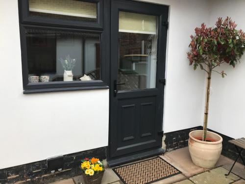 a black door with a window and a potted plant at The Retreat in Sheringham