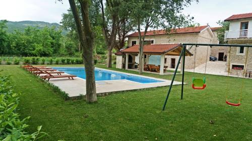 a yard with a pool with a swing and a house at Stara kuća Estate in Ljubuški