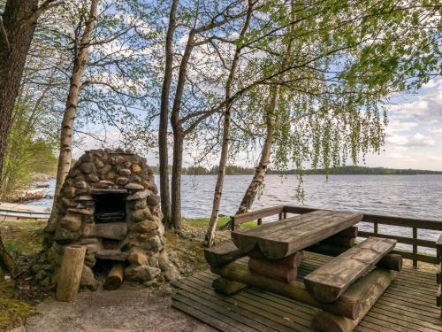einen Picknicktisch und einen Steinofen neben einem See in der Unterkunft Holiday Home Mäntyrinne by Interhome in Haapaniemi