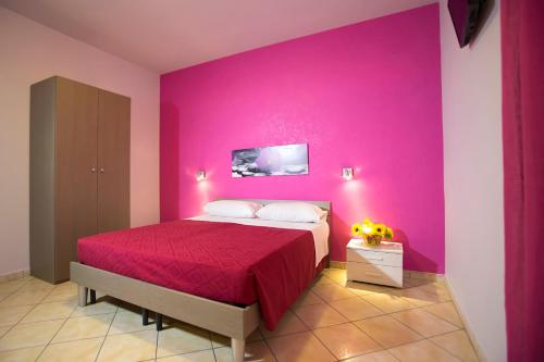 Un dormitorio con una pared rosa y una cama en Il Tipico en Trapani