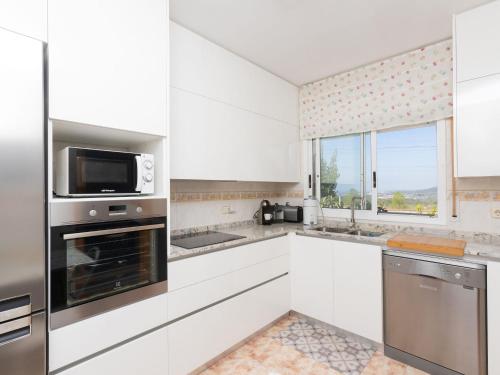 カラフェルにあるHoliday Home Oasis by Interhomeの白いキャビネット、電子レンジ、窓付きのキッチン