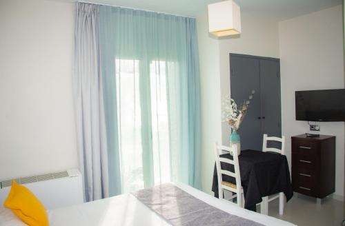 a bedroom with a bed and a table and a window at Hotel et Appartements Reine D'Azur in Roquebrune-Cap-Martin