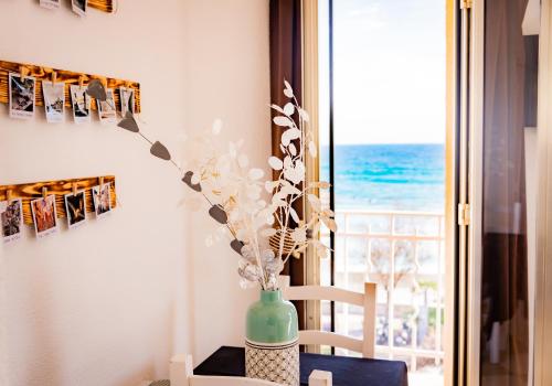 a vase of flowers sitting on a table in front of a window at Hotel et Appartements Reine D'Azur in Roquebrune-Cap-Martin