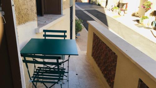 a green table and chairs sitting on a balcony at Le colostre T2 in Saint-Martin-de-Brômes